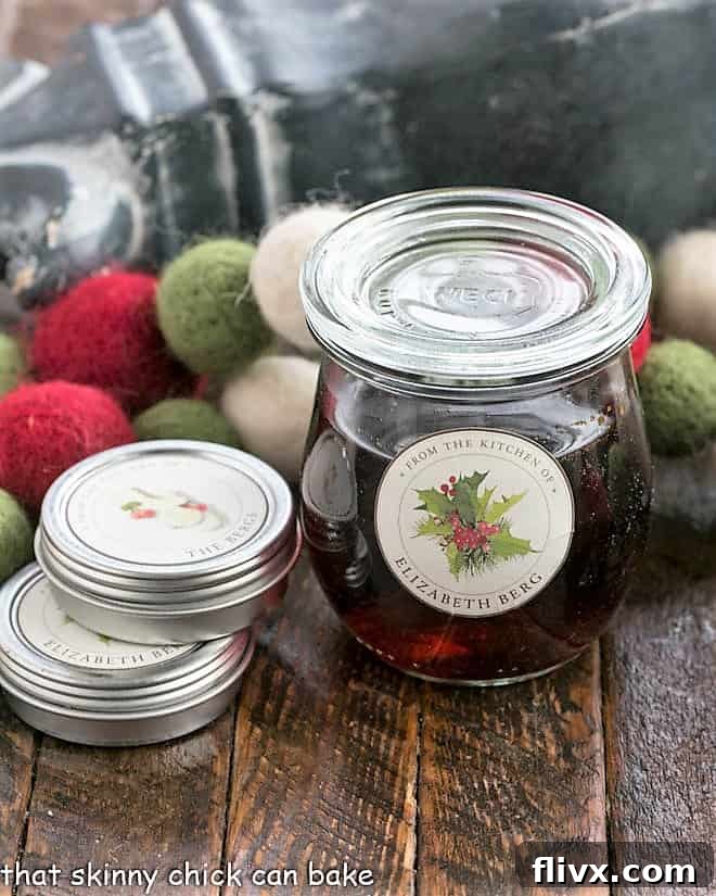 A Weck jar filled with homemade vanilla extract next to two tins of decorative labels, ready for bottling and gifting.