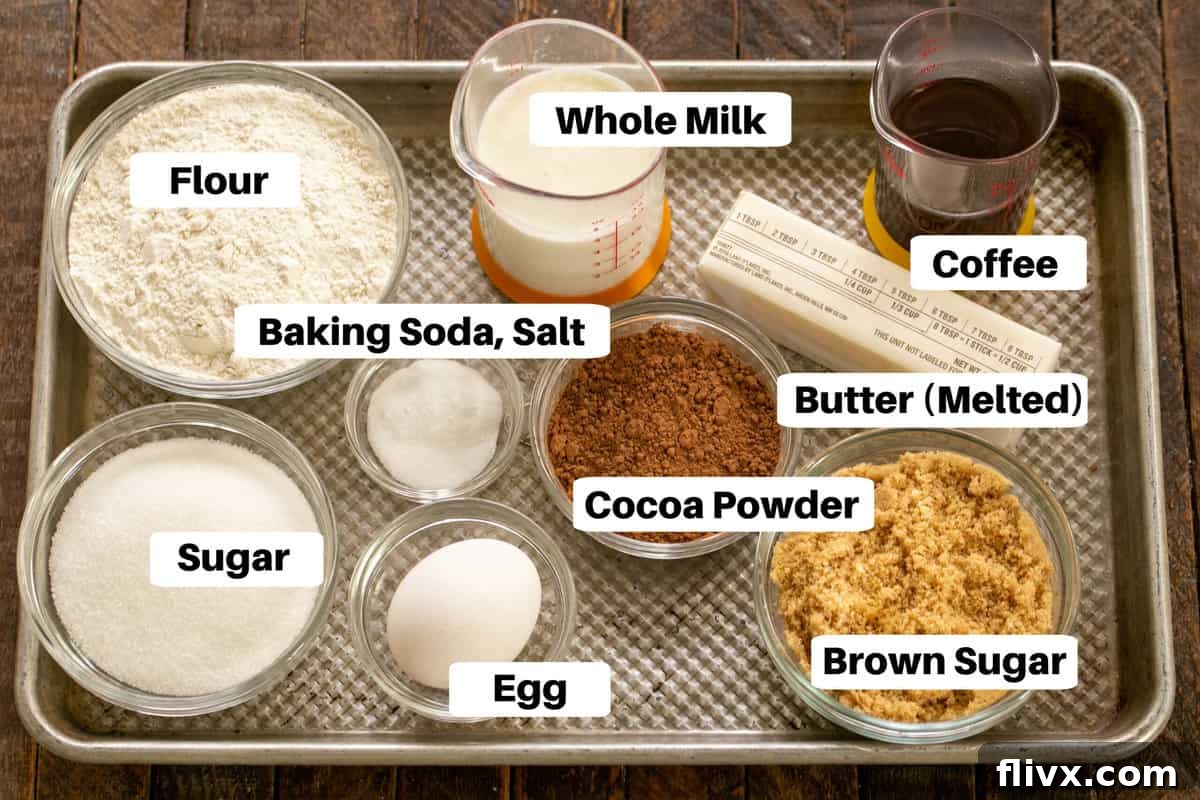 Various Ghirardelli Dark Chocolate Cupcake ingredients laid out on a metal sheet pan, clearly labeled for easy identification.