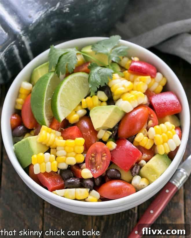 Close-up view of a vibrant Fresh Corn and Black Bean Salad with avocado, lime, and cilantro in a white ceramic bowl, ready to be served at a summer gathering.