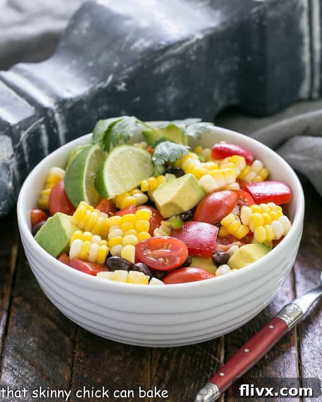 A small serving bowl filled with vibrant Fresh Corn and Black Bean Salad, garnished with a lime wedge and fresh cilantro, perfect for a single serving or as part of a meal.