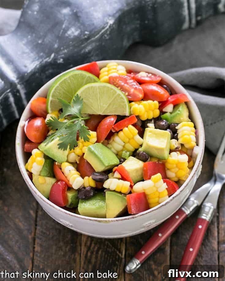 Vibrant Fresh Corn and Black Bean Salad with avocado in a white bowl, ready to be served, highlighting a healthy and colorful summer dish.