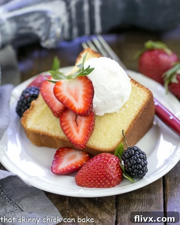 A delectable slice of the Best Pound Cake, elegantly topped with fresh, vibrant berries and a dollop of fluffy whipped cream, highlighting its dense, tender crumb.