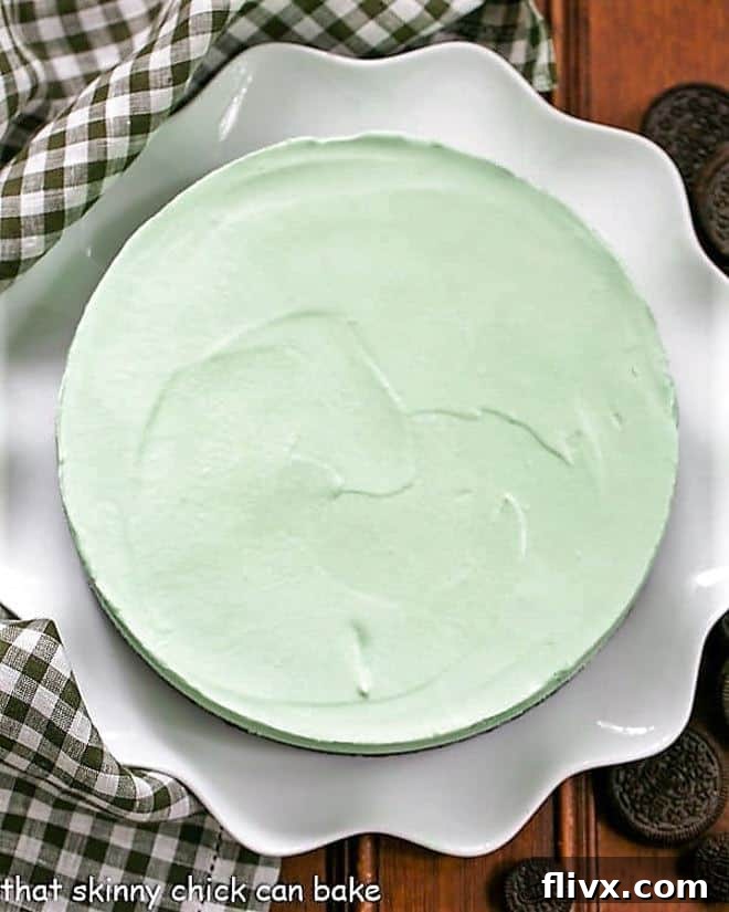 Frozen Mint Pie with an Oreo Crust: The Perfect Cooling Dessert! A whole Frozen Grasshopper Pie with an Oreo Crust, showcased on a pristine white ceramic serving platter, ready to be sliced.