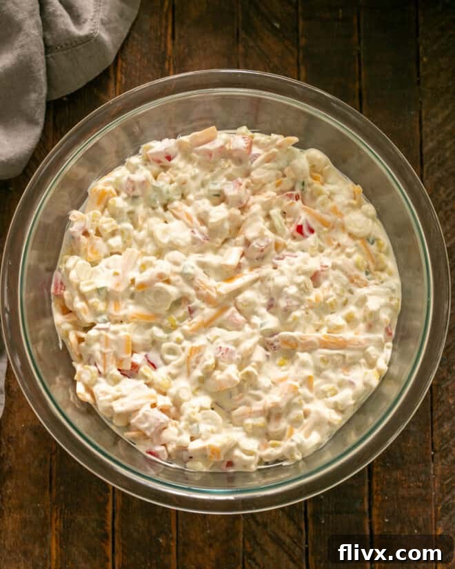 Hands carefully mixing the dressing and all the other dip ingredients together in a bowl until everything is evenly incorporated.