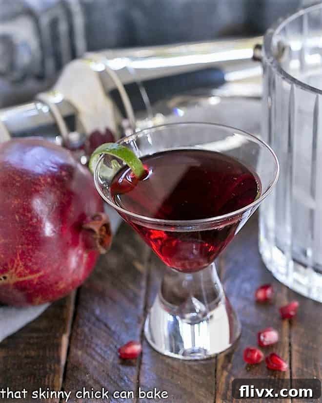 A single Pomegranate Cosmopolitan Cocktail in a martini glass, garnished with a lime twist.