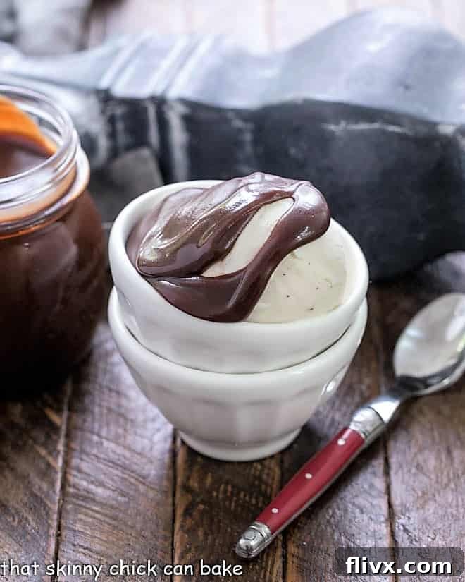 Homemade Hot Fudge Sauce: Rich and decadent chocolate topping for ice cream and more! Make it at home. A scoop of creamy vanilla ice cream generously topped with rich, dark homemade hot fudge sauce in stacked white bowls, ready to be enjoyed.