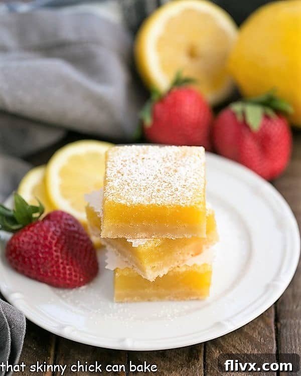 The Best Lemon Bars stacked on a white dessert plate, showing off their thick lemon filling and golden shortbread crust.