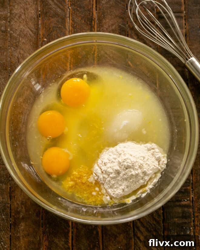 Lemon Custard Ingredients in a Mixing Bowl, showing eggs, sugar, lemon juice, zest, and flour before whisking.
