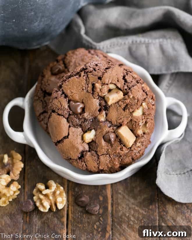 A small white terrine filled with perfectly baked Chocolate Toffee Cookies, displaying their cracked tops and rich texture.