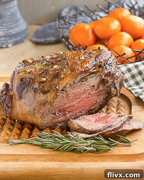 A beautifully roasted glazed leg of lamb studded with garlic and rosemary, resting on a cutting board, ready to be carved.