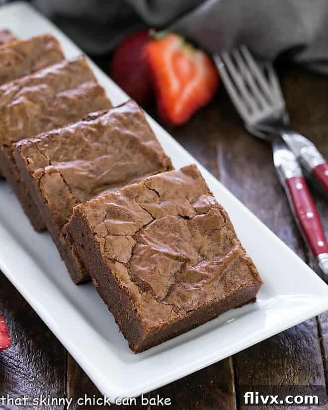 Decadent Fudgy Brownies from Scratch arranged artfully on a white ceramic serving platter, showcasing their rich, dark chocolate color and irresistible texture.