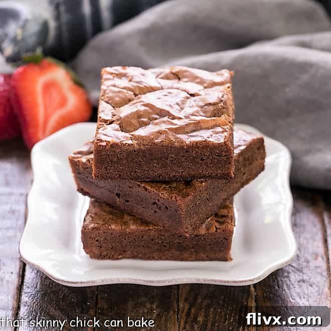 3 fudgy homemade Brownies stacked on a square white plate