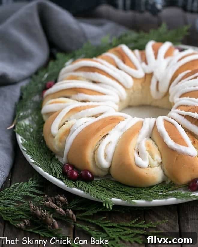 A festive Cream Cheese Tea Roll, garnished with vibrant fresh cranberries and green evergreen sprigs, making it a perfect holiday brunch centerpiece.