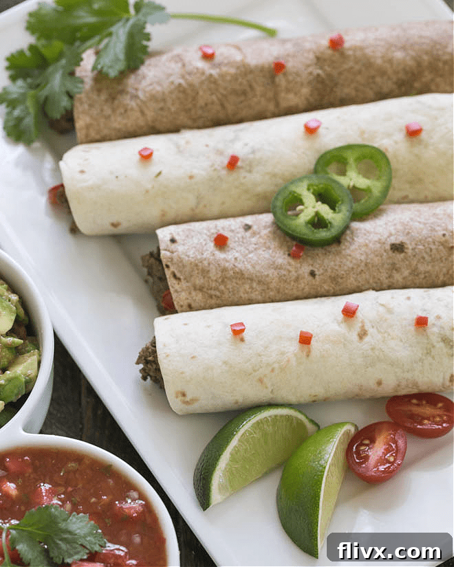 Overhead view of soft shell beef tacos on a white platter, garnished with fresh cilantro and lime wedges.