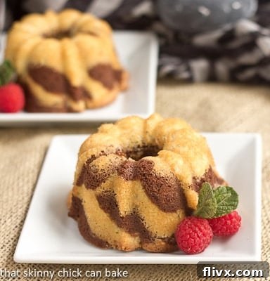 Two mini bundt cakes on square white plates, showcasing the zebra pattern of individual chocolate and vanilla marble cakes.