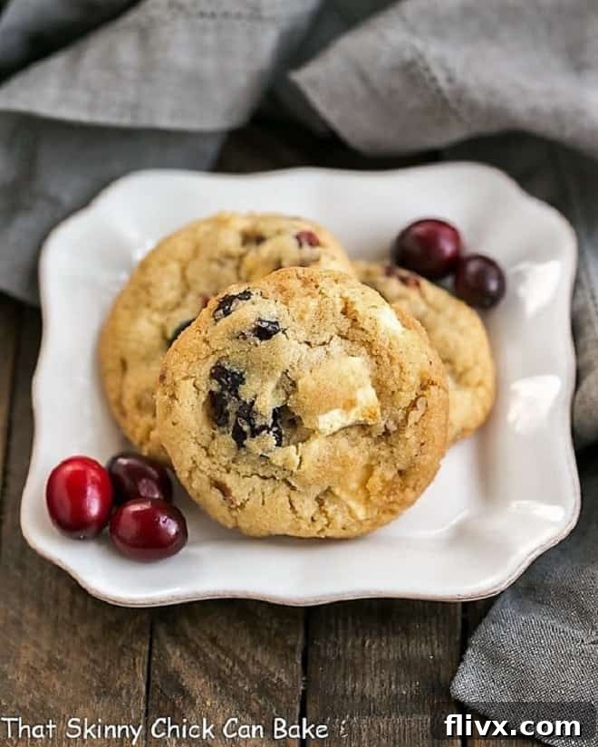 Cranberry, White Chocolate, Crystallized Ginger Cookies on a square white plate with fresh cranberries, a delicious holiday cookie.