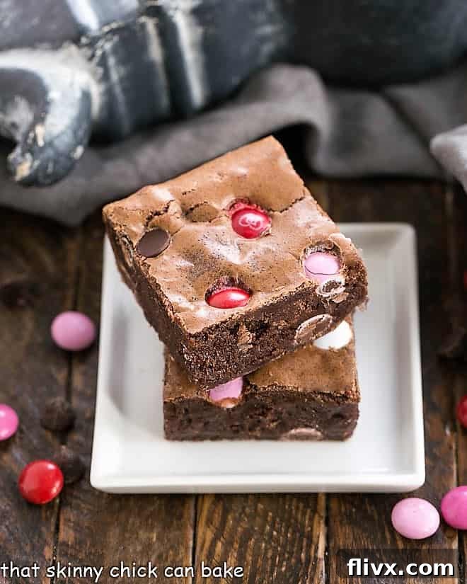 Fudgy brownies with M&M's stacked on a small white plate