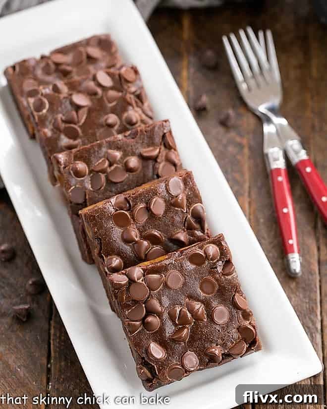 Overhead view of slices Caramel Brownies on a white rectangular tray with a couple of red handled forks.