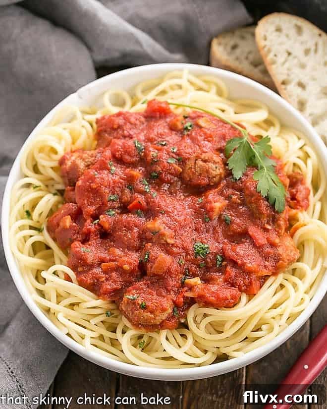 Overhead view of a generous serving of homemade pasta sauce generously spooned over a bed of spaghetti, ready to be enjoyed.