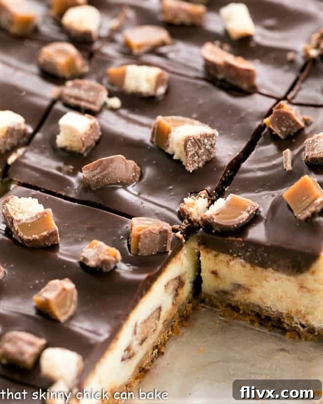 Close up of a pan of perfectly sliced Twix Cheesecake Bars, showing the distinct layers.