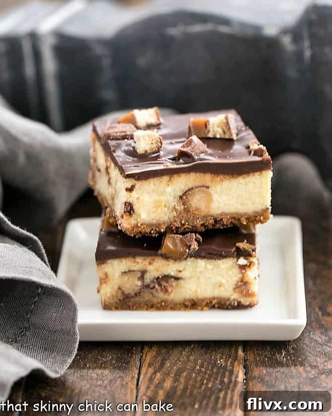 Two Twix Cheesecake Bars stacked on a square white plate, showing their delicious layers.