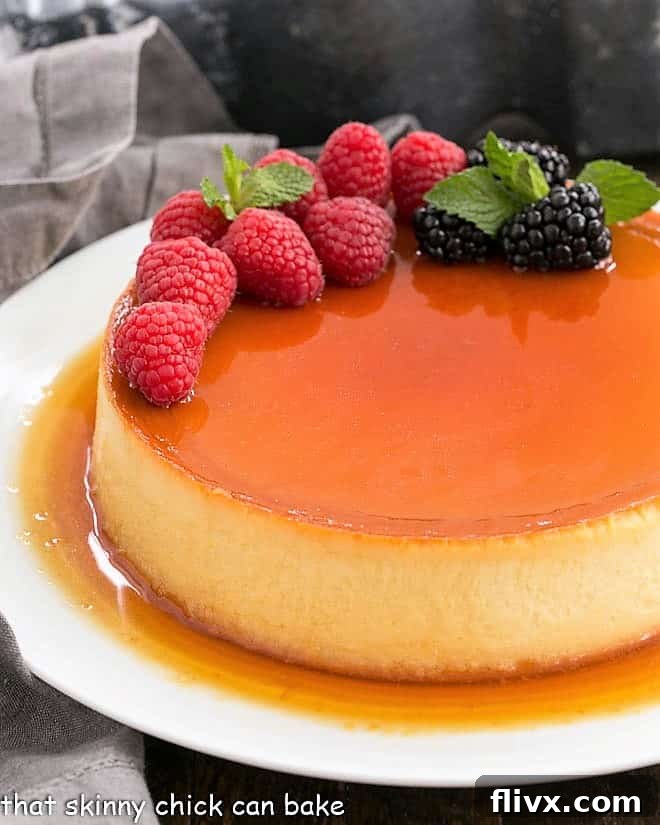 Flan Recipe topped with berries on a white plate. A rich and dreamy Cream Cheese Caramel Flan, a cross between creme brulee and cheesecake, that everyone will want to lick their plates clean!