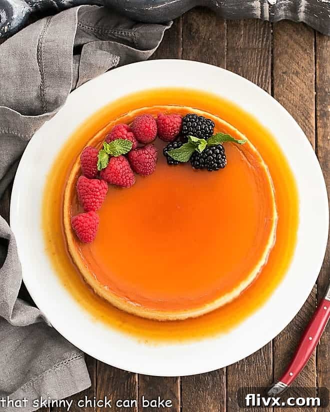 Overhead view of Cream Cheese Flan on a white serving plate. A rich and dreamy leche Flan, a cross between creme brulee and cheesecake, that everyone will want to lick their plates clean!