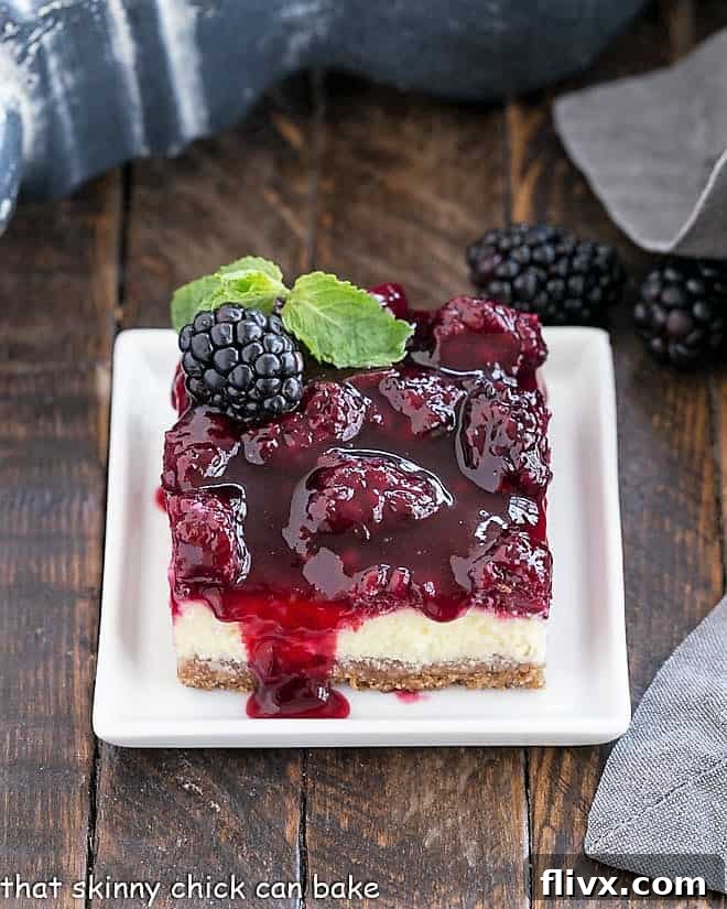 A single Blackberry Cheesecake Bar with a vibrant berry topping and a fresh sprig of mint, artfully presented on a square white plate.