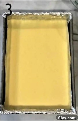 Smooth cheesecake filling spread over the prepared crust in a baking pan, ready for baking.