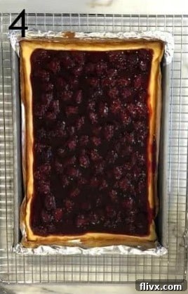 Vibrant blackberry topping generously spread over the cooled cheesecake layer in a baking pan.