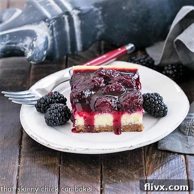 Blackberry Topped cheesecake bar with fresh blackberries on a round white plate