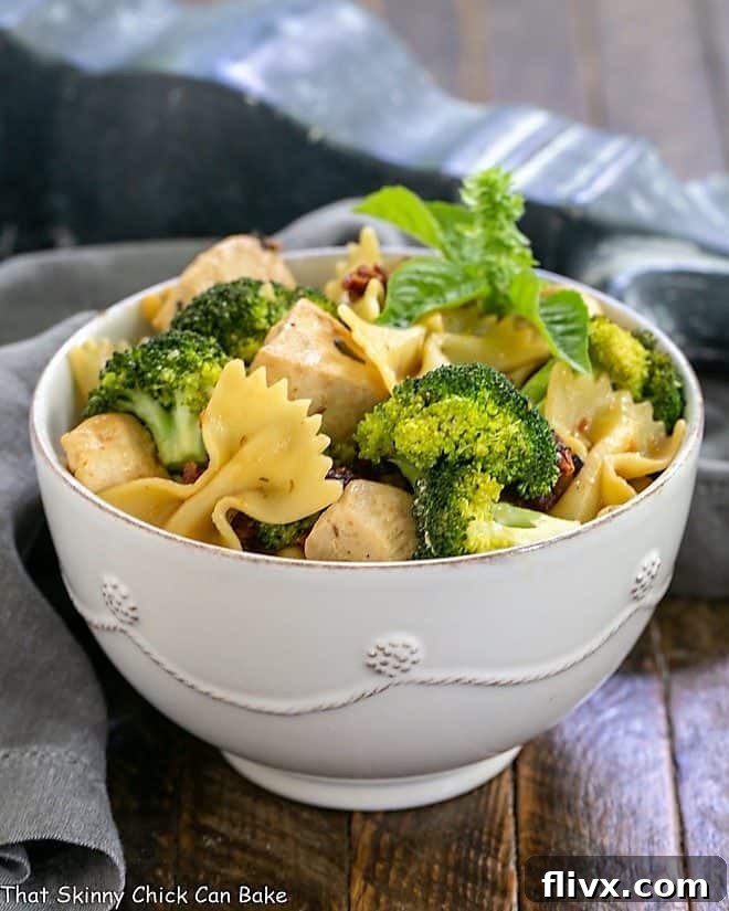 Chicken with Broccoli, Sun-dried Tomatoes and Bow Tie Pasta in a white ceramic bowl, tossed with a light sauce
