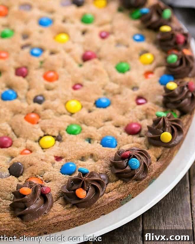 Close view of chocolate chip cookie cake, generously topped with colorful M&M's