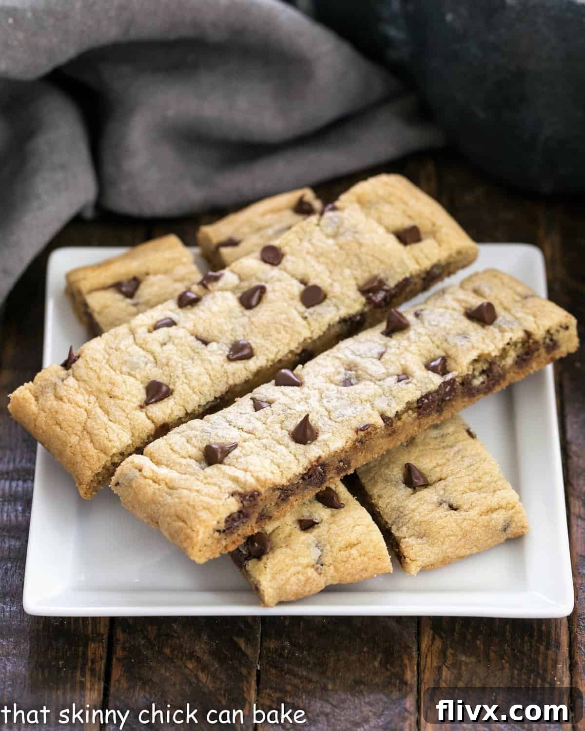 Four golden-brown chocolate chip cookie sticks arranged neatly on a square white plate, ready for a delightful snack.
