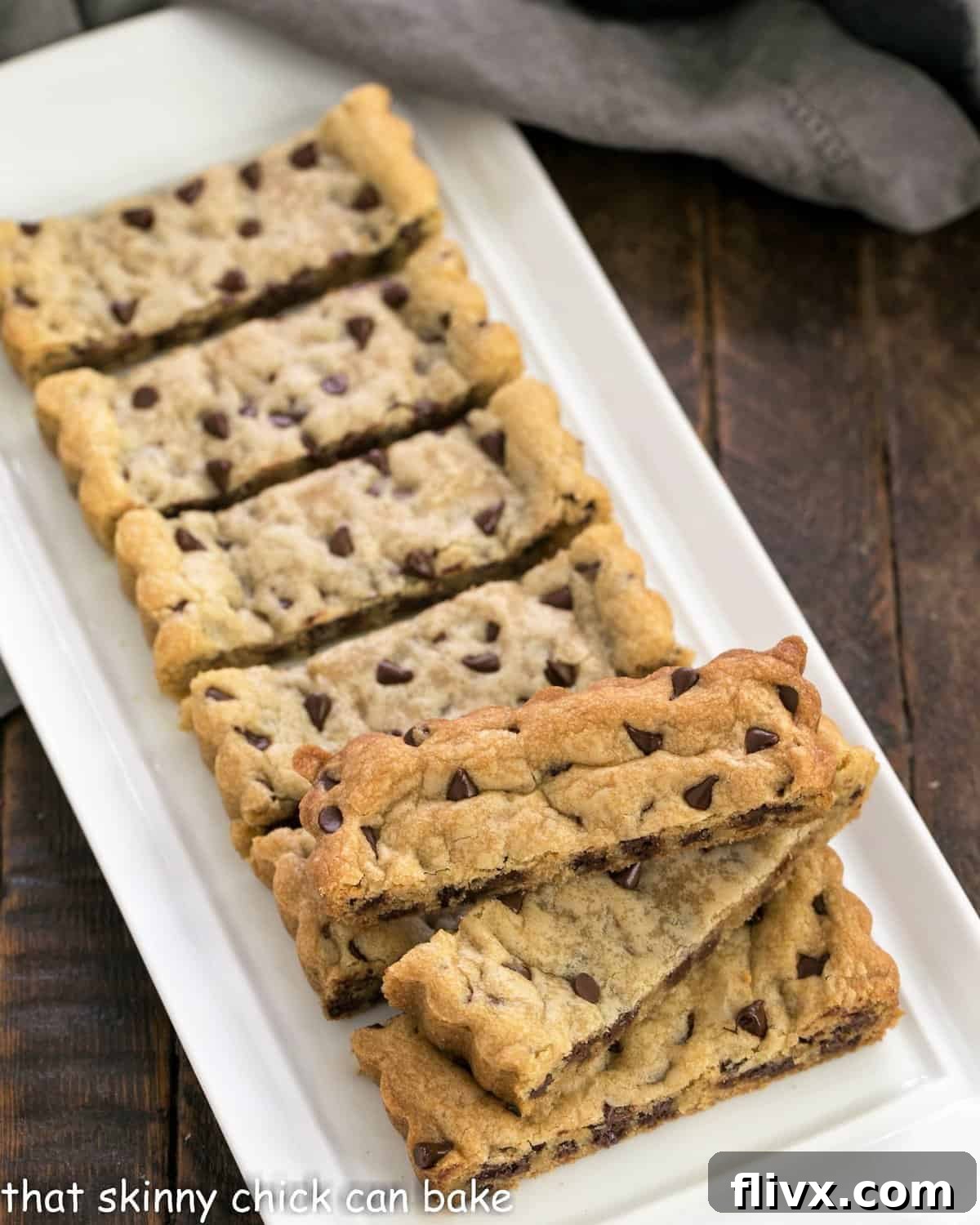 An array of freshly baked chocolate chip cookie bars displayed on a elegant white ceramic tray, perfect for sharing.
