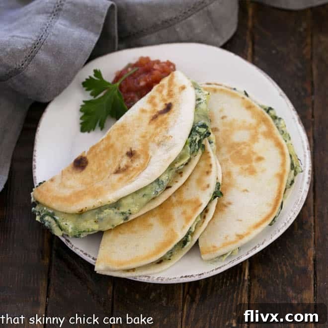 Overhead view of spinach dip quesadillas cut in half on a round white plate with salsa and a sprig of parsley