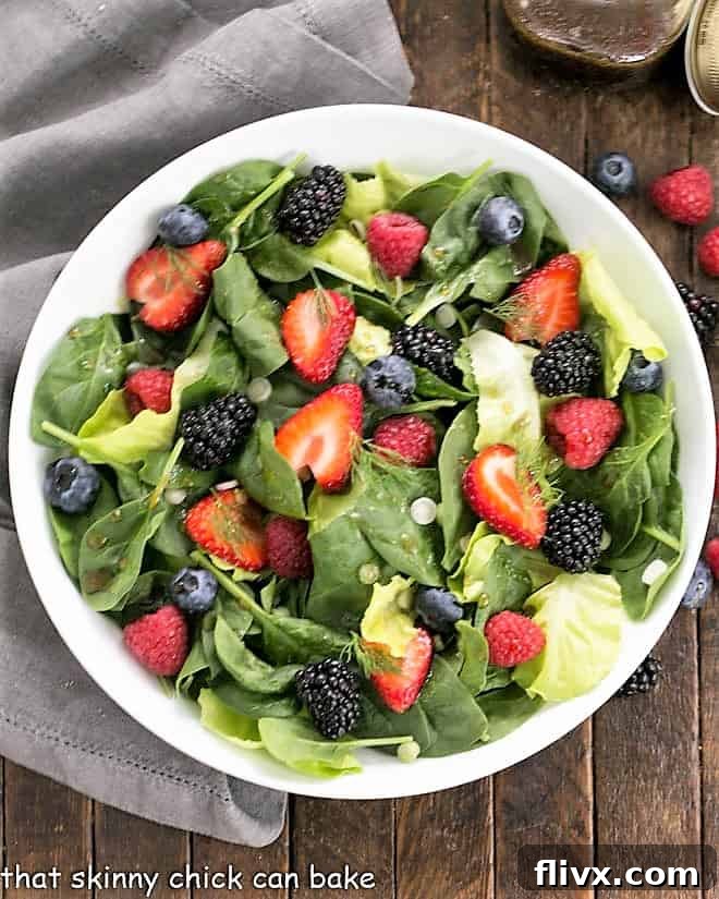 Overhead view of Spinach Almond and Berries Salad in a white bowl.