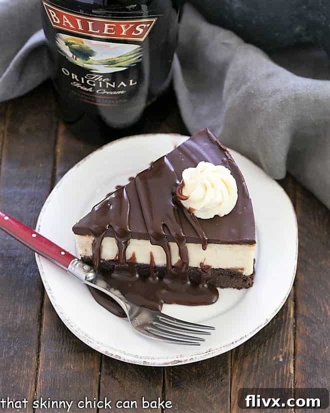 Overhead view of a slice of brownie cheesecake garnished with whipped cream and fudge sauce.