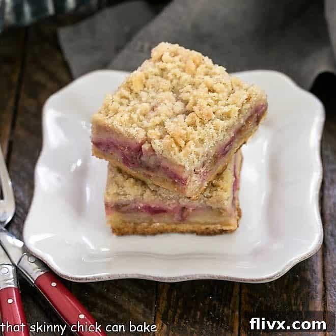 Rhubarb Crumble Bars 3 Two Streusel Topped Rhubarb Bars stacked elegantly on a white plate, highlighting their delightful layers and enticing texture.