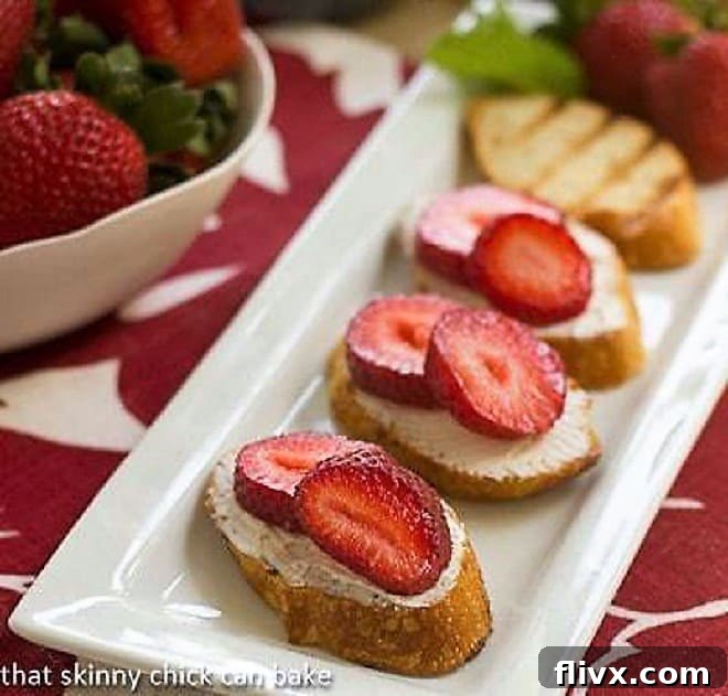 Strawberry Tartines lined up on a white platter, showcasing the fresh strawberries and goat cheese on toasted baguette.