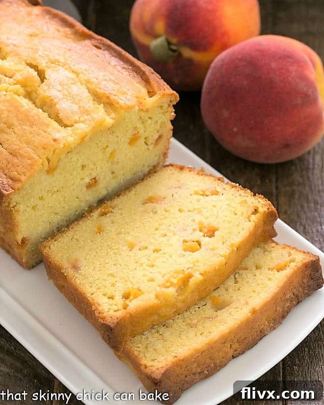 Sliced Glazed Peach Pound Cake on a white ceramic tray, showing off the perfectly baked golden crust and visible peach pieces within.