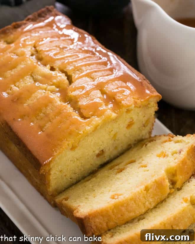 Glazed Peach Pound Cake sliced on a white tray, highlighting the vibrant glaze and inviting texture.