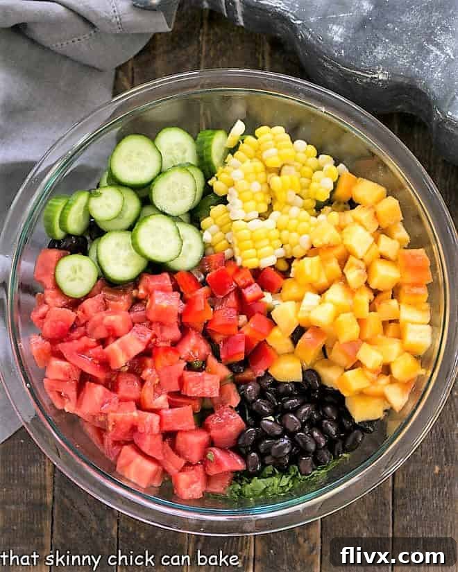 First step for Southwest Chopped Salad: chopped fresh vegetables including corn, bell peppers, tomatoes, and peaches, along with ingredients for a dressing.