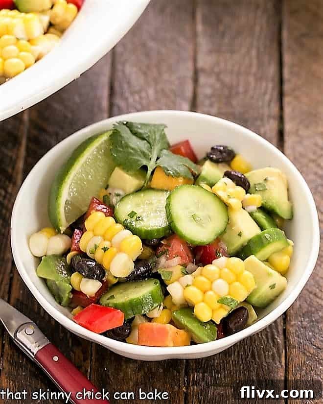 A small white bowl filled with a colorful black bean and corn salad, garnished with fresh cilantro.