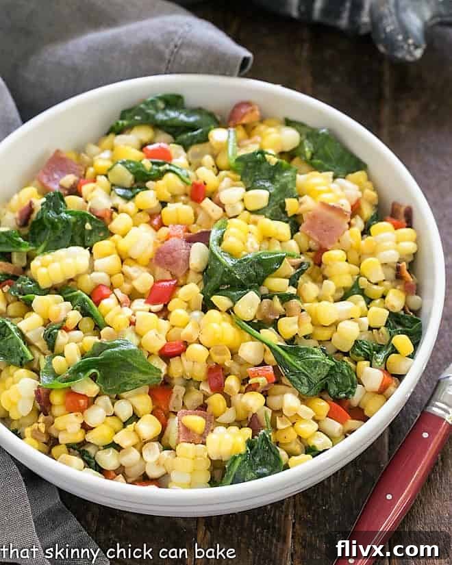 Overhead view of a white bowl filled with Skillet Corn with Spinach and Peppers, garnished with fresh herbs, ready to be served as a vibrant summer side dish.