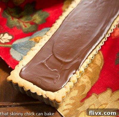 Chocolate Chip Cookie Tart with Caramel and Chocolate Glaze in a rectangular tart pan, before being sliced.