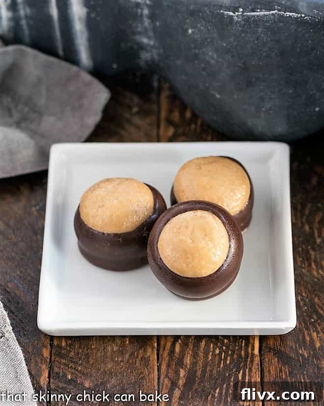 A trio of delicious Chocolate Peanut Butter Bon Bons, each featuring a rich peanut butter center and a half-dipped chocolate shell, elegantly presented beside a pristine square white plate, ready to be enjoyed as a classic, homemade treat.