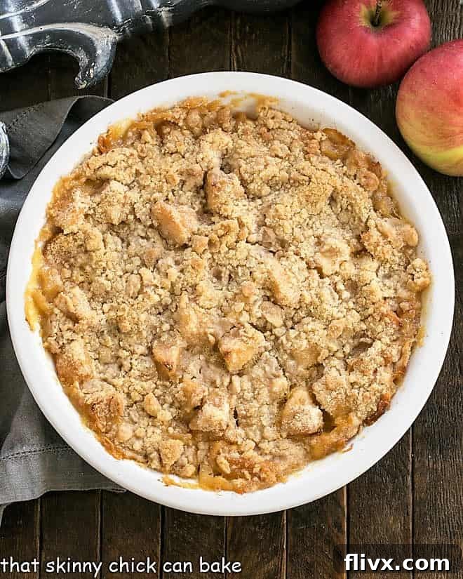 An overhead shot of a golden-brown apple crumble cooling in a white ceramic pie dish, showcasing its perfect texture.