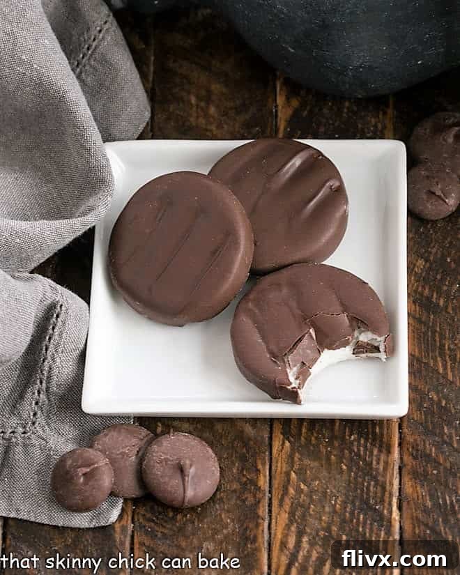 Overhead view of three perfectly round homemade peppermint patties resting on a square white plate, ready to be enjoyed.