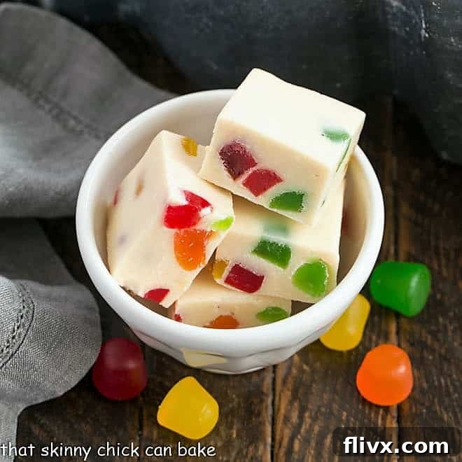 Small white bowl filled with squares of white chocolate fudge, studded with colorful gumdrops.